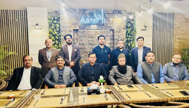 Taimoor Bamazai with a group seated at a dinner table under an Aanch sign
