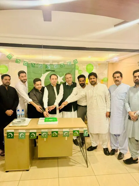 Taimoor Bamazai and colleagues cutting a cake under green and white bunting