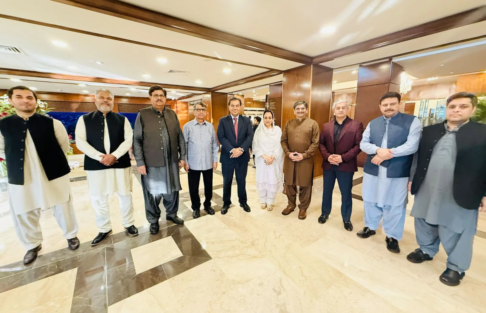 Taimoor Bamazai standing in a row of ten people in a hotel lobby