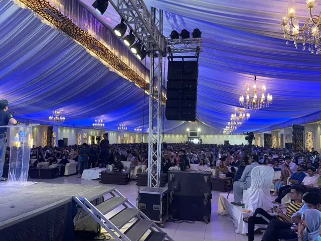 A large seminar hall with a lit stage and a seated audience