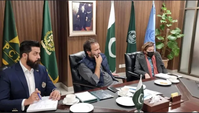 A formal meeting around a conference table with Pakistan flags